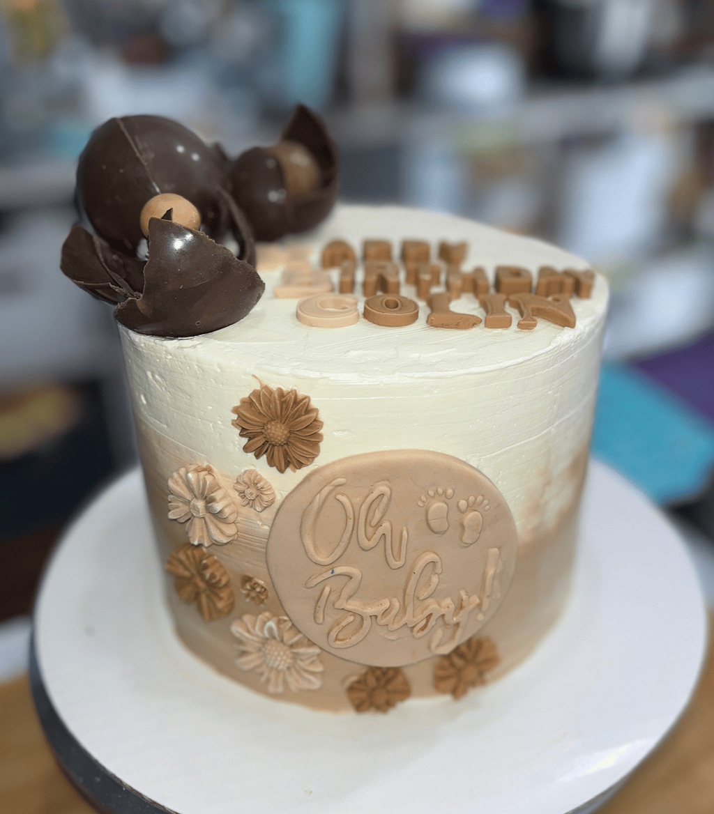 Beige and White Baby Shower Cake with Floral and Chocolate Decorations